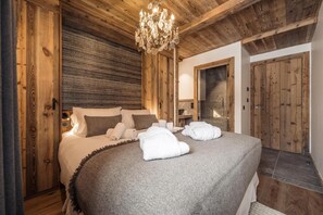 Relax in this cozy retreat with a large bed, chandelier, and wooden paneling.