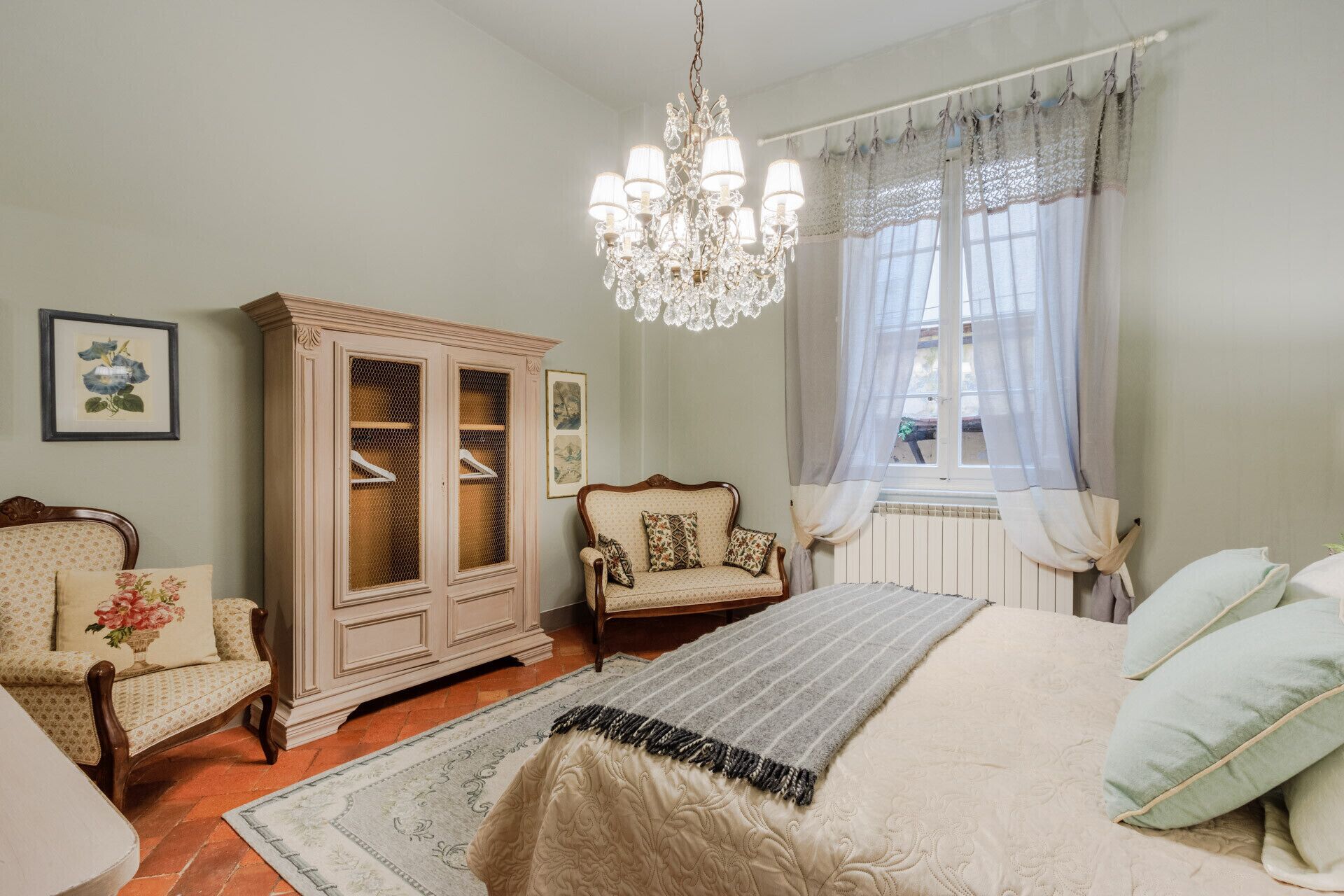 Une pièce comprenant un lit, une armoire en bois, un canapé et un lustre.