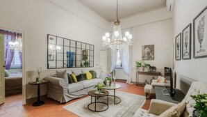 A living room with a sofa, armchairs, a chandelier, a mirror, and artwork on the walls. - Casa Celeste 3 Bedrooms Apartment with Terrace Inside Lucca (Lucca)