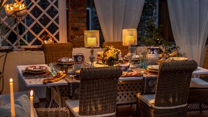 An outdoor dining area with wicker furniture, candles, and a table set for a meal. - Casa Celeste 3 Bedrooms Apartment with Terrace Inside Lucca (Lucca)