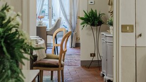 A hallway leading to a dining area with a table and chairs, a potted plant, and a refrigerator. - Casa Celeste 3 Bedrooms Apartment with Terrace Inside Lucca (Lucca)