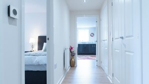 Ein Flur mit einem Bett, einem Heizkörper und einer weiter hinten liegenden Küchenzeile.