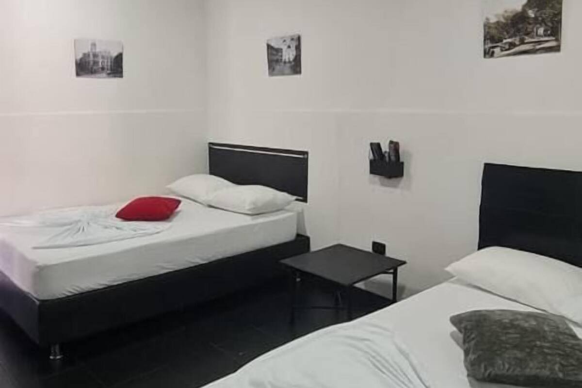 Una habitación de hotel con dos camas, una mesita y un ventilador de techo.