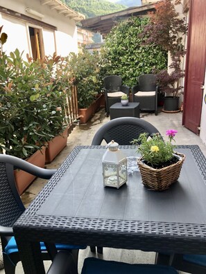 An outdoor patio with a table, chairs, potted plants, and a lantern. - Appartamento Simona Comfort&relax in Centro Paese (Castiglione dei Pepoli)