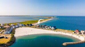 An aerial view of a coastal area with a beach, houses, and a lighthouse. - Luxus Beachvilla "the View" (Ostseeresort Olpenitz)