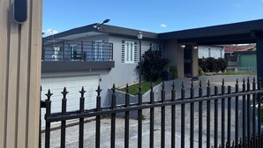 A modern two-story house with a garage, a balcony, and a fenced driveway.