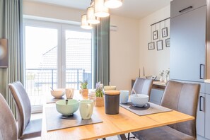 A dining area with a wooden table, chairs, and various bowls and containers.