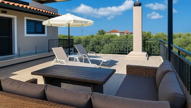 Un espace extérieur abrité, aménagé avec une table, des chaises et un canapé.