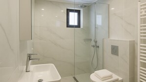 Une salle de bain moderne avec une douche à parois de verre, un lavabo blanc et des toilettes.