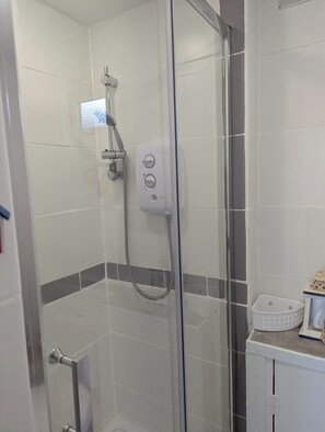 A glass-enclosed shower with a handheld showerhead and a wall-mounted control panel. - Pet friendly chalet ..  Sleeps 5
 (Bude)