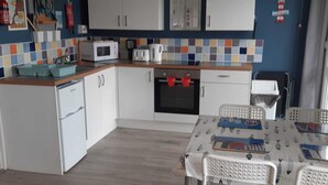 Une cuisine compacte avec des meubles blancs, un four à micro-ondes, un grille-pain et un petit réfrigérateur.