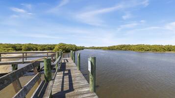 A wooden pier extending into a calm river, surrounded by dense greenery.
