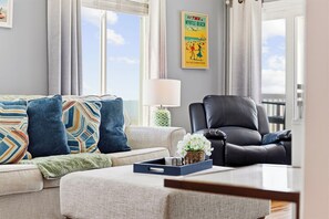 Ein Wohnzimmer mit einer Couch, einem Sessel, einer Lampe und einem Fenster mit Blick.