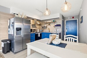 Una cocina compacta con un refrigerador de acero inoxidable, un microondas y una cafetera.