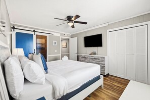 Ein Schlafzimmer mit Bett, Deckenventilator, Fernseher, Kleiderschrank und Schreibtisch.