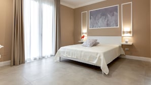 Un dormitorio moderno con una cama grande, paredes color beige y un amplio ventanal con cortinas.