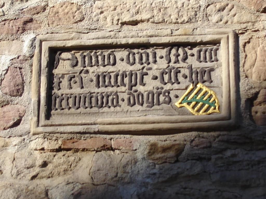 A stone plaque with carved text and a shield emblem.