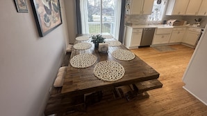 Un comedor con una mesa de madera, individuales tejidos y vista al patio trasero a través de una ventana.