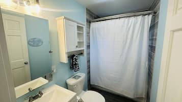 Un baño con lavamanos, inodoro y cortina de ducha.