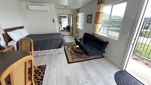 A bedroom with a bed, a sofa, a chair, and a dining table. - New Private Studio - UCR - LLU (Riverside)
