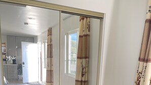 A room with a large mirror reflecting a hallway, a patterned rug, and a window with curtains. - New Private Studio - UCR - LLU (Riverside)