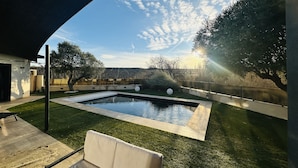 Ett modernt utomhusområde med en pool, en solstol, en pergola och utsikt över det omgivande landskapet.