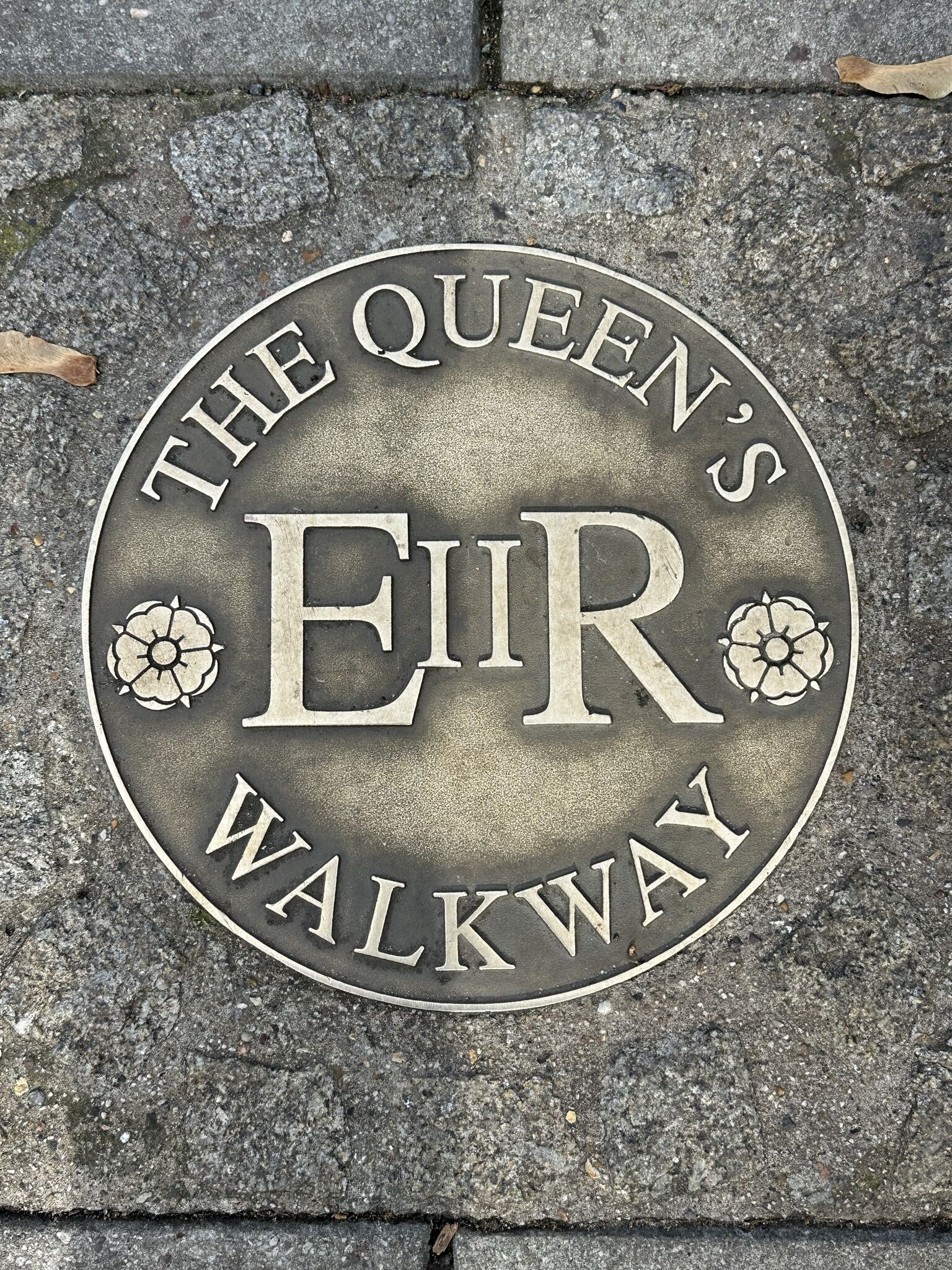 Une plaque métallique circulaire portant l’inscription : « The Queen’s EIR Walkway ».