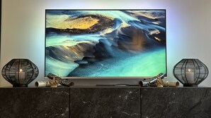 Un televisor de pantalla plana fixat a una paret de marbre, amb dues làmpades metàl·liques decoratives als costats.