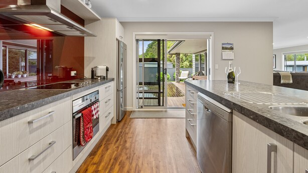 Una cucina moderna con elettrodomestici in acciaio inossidabile, un'isola grande e una porta scorrevole in vetro che dà su un patio.
