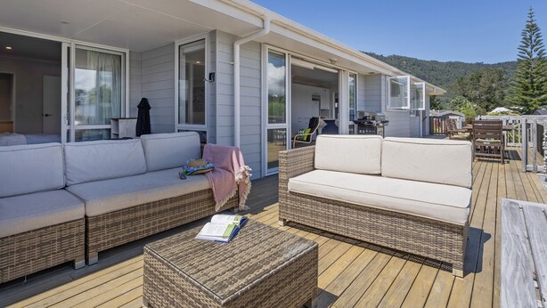 A covered outdoor area with wicker furniture and a book on a table. - Family Oasis - Pauanui Holiday Home (Pauanui)