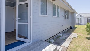 A single-story mobile home with a sliding glass door, a small porch, and a clear sky. - Family Oasis - Pauanui Holiday Home (Pauanui)