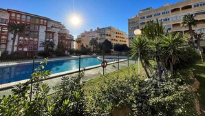 A swimming pool surrounded by greenery and buildings.