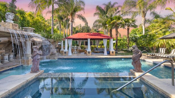 A pool area with a waterfall, a gazebo, and lounge chairs. - Erwin Estate (Woodland Hills)
