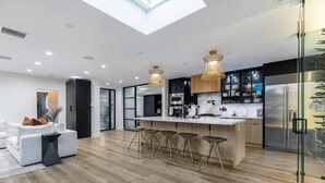A modern kitchen with a central island, bar stools, and a glass-fronted refrigerator. - Erwin Estate (Woodland Hills)