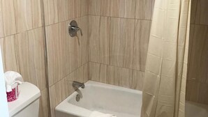 Un baño con bañera, inodoro y cortina de ducha.