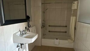 Un baño con lavamanos, espejo, ducha y bañera.