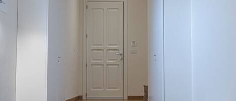 Un pasillo con una escalera que lleva a una puerta, una zona de bar con taburetes y un mueble con un objeto decorativo encima.