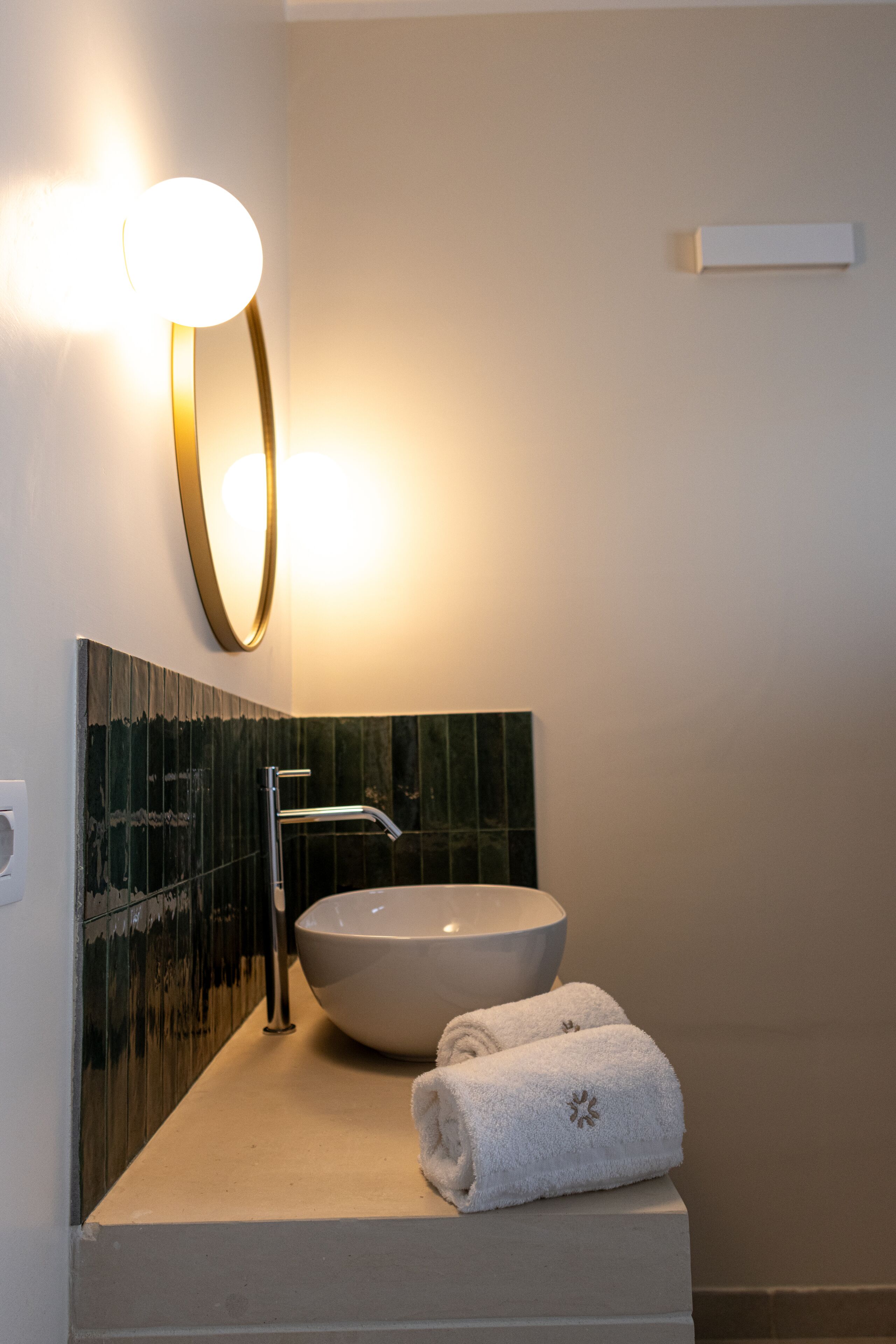 A bathroom with a large vessel sink, a wall-mounted mirror, and a towel on the counter.