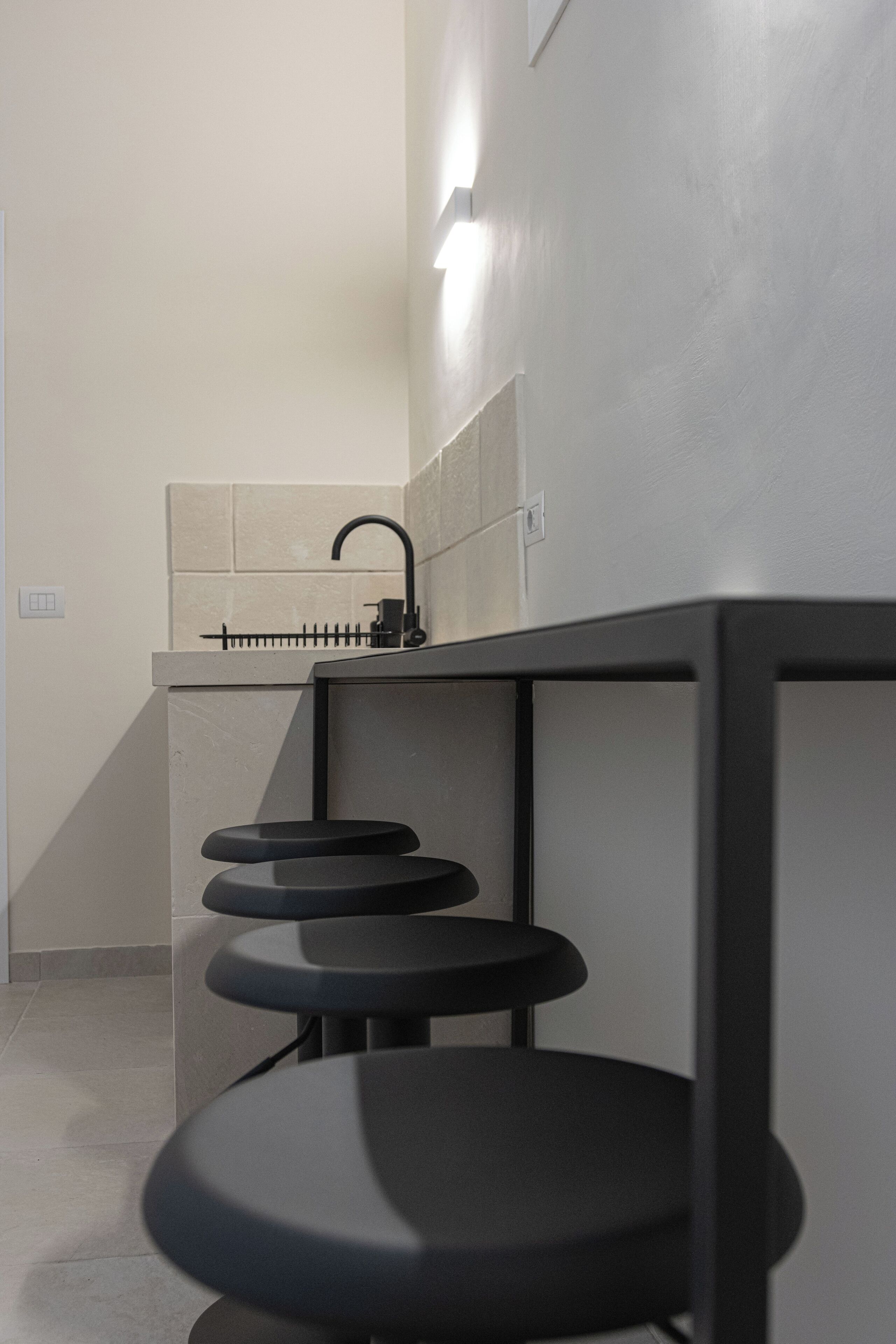 Een moderne badkamer met een wastafel, een spiegel en drie zwarte krukken.