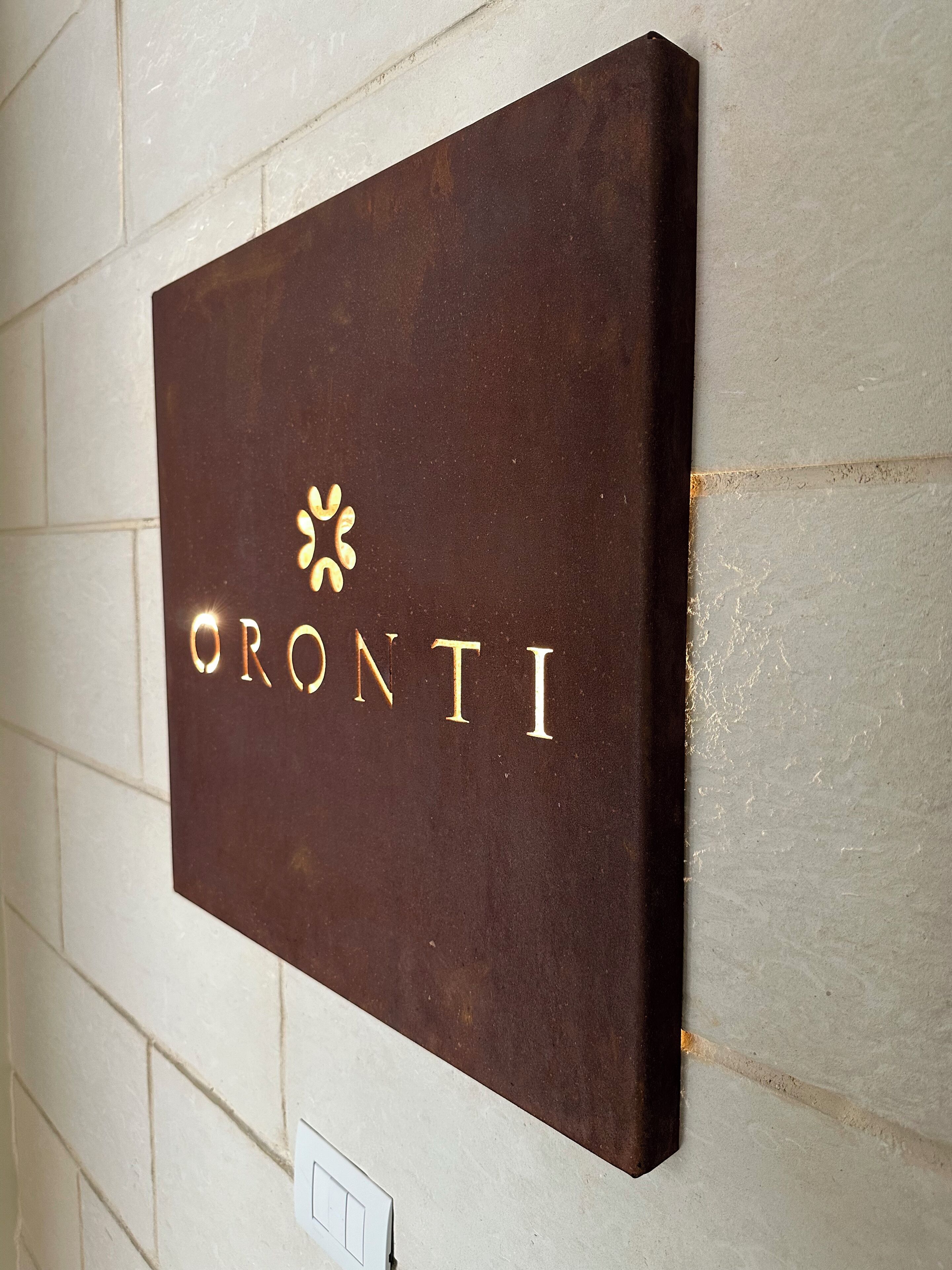 Une enseigne portant le nom « ORONTI » est fixée à un mur.