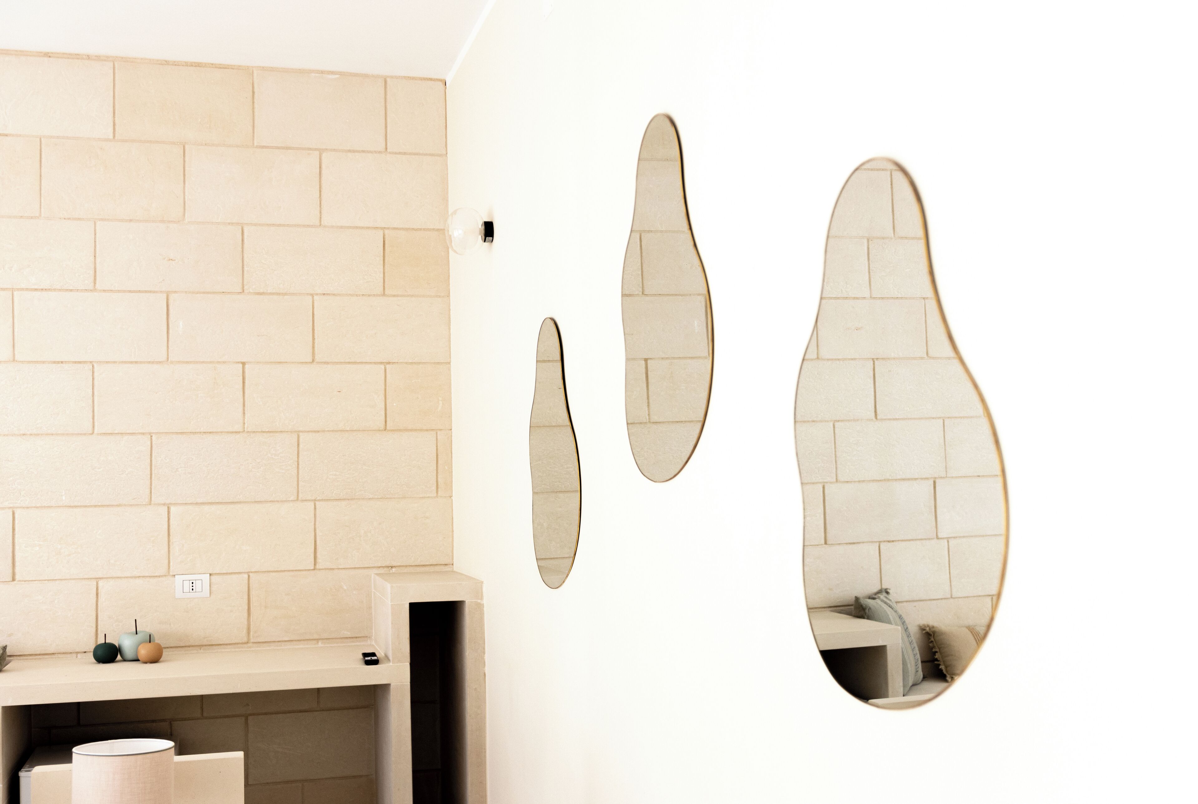 Un baño con pared de azulejos color crema, un lavamanos con espejo y un perchero para toallas.