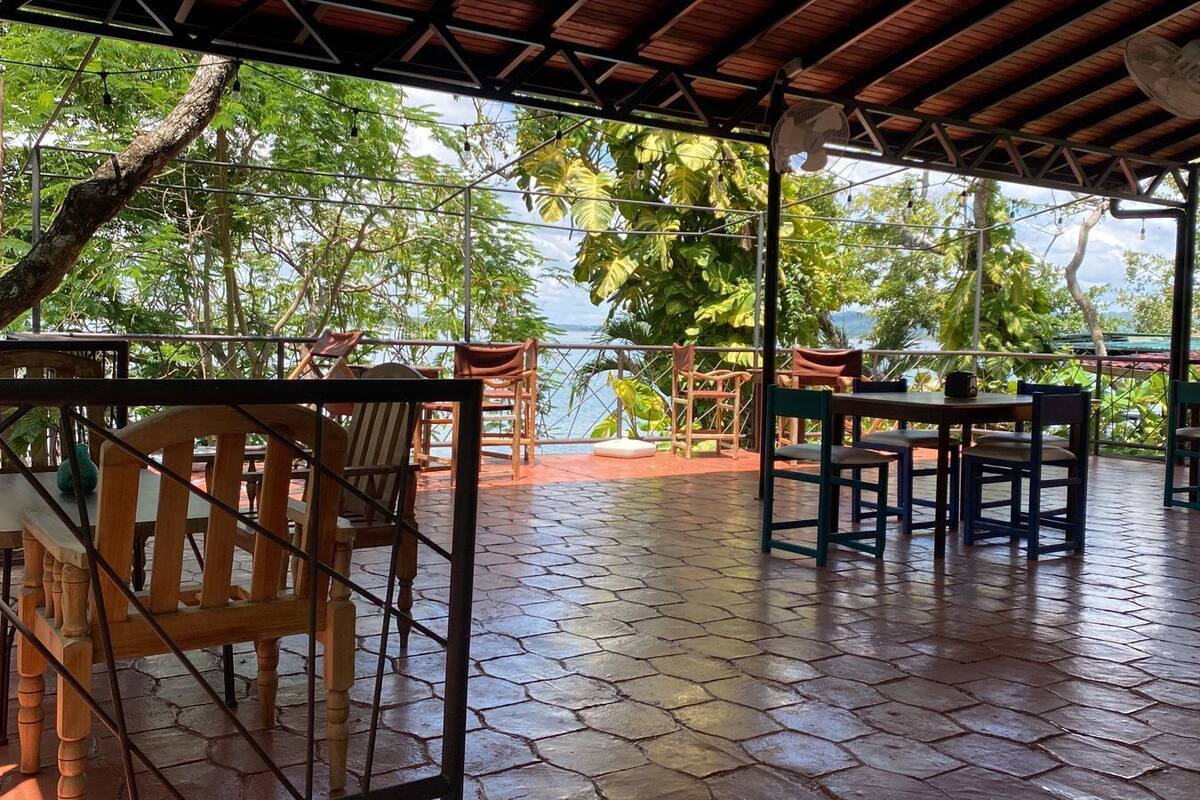 Eine Terrasse im Freien mit Holzmöbeln und Blick auf das Meer.