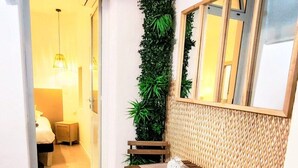 A compact room with a small table and two chairs, a vertical garden, a woven wall panel, and a door leading to another room. - Kosykasa Spa (Cannes)