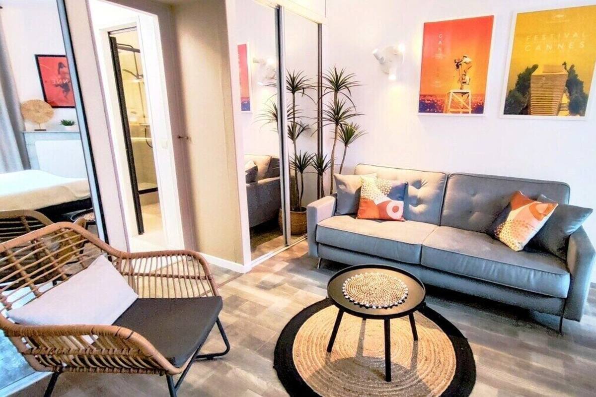 A modern living room with a grey sofa, wicker chairs, and a round coffee table.