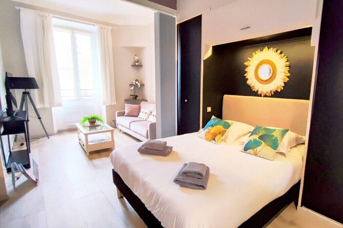 A modern bedroom with a large bed, a sunburst wall decoration, and a view of the room's interior.