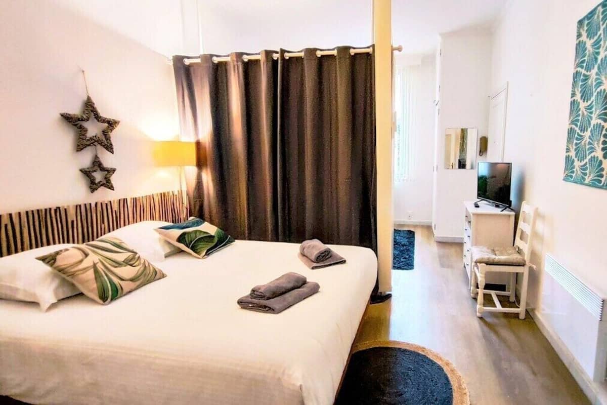 A hotel room with a bed, a desk, a chair, a TV, and a decorative mirror.