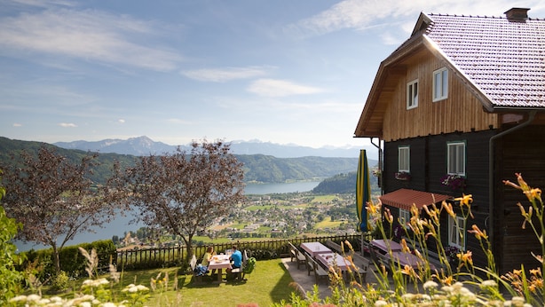 Ein Holzhäuschen mit Blick auf einen See und Berge.