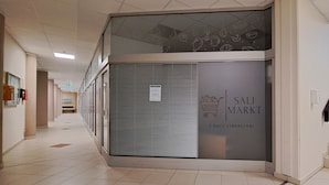 Ein Flur mit einer geschlossenen Schiebetür mit der Aufschrift 'SALI MARKET' und einer Treppe auf der rechten Seite.