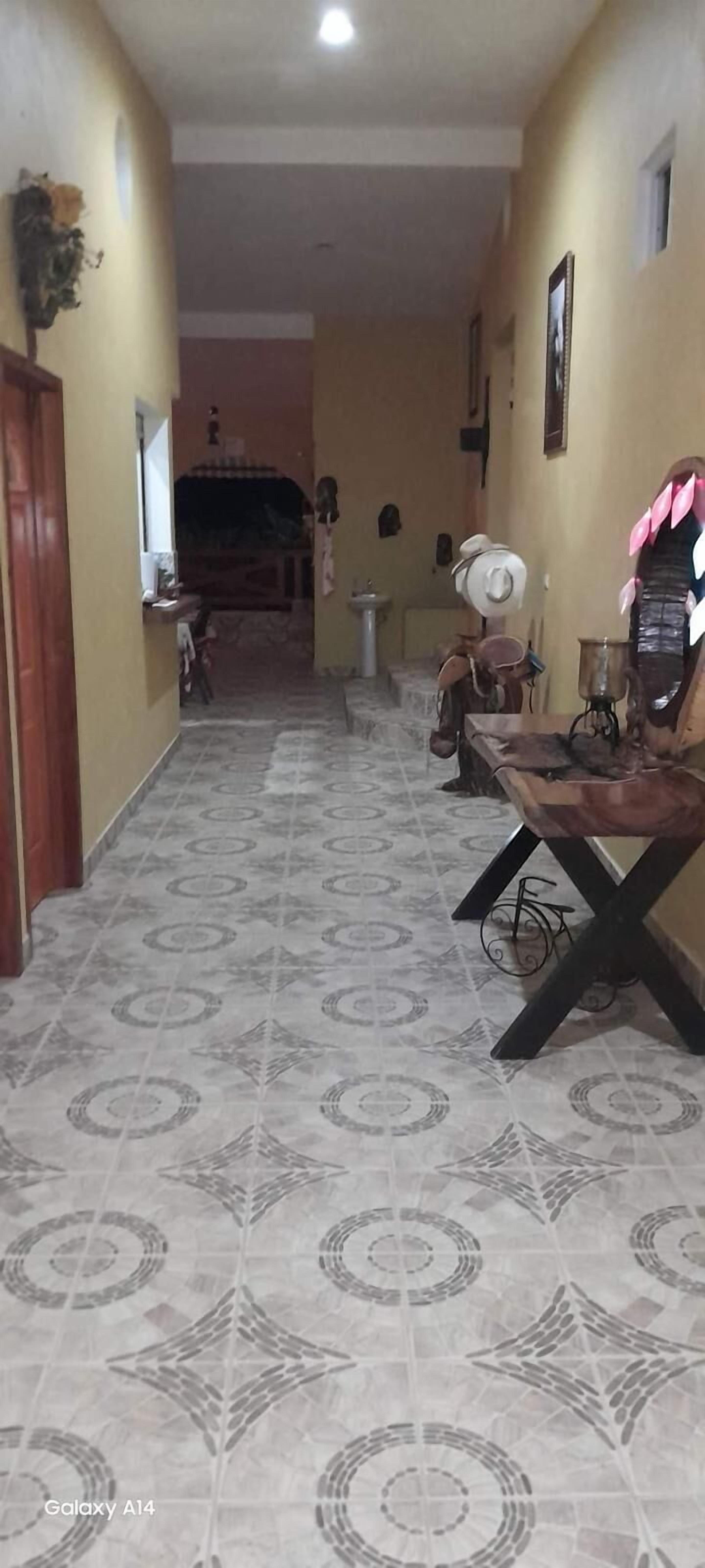 A hallway with patterned floor tiles, a wooden door, and a table with a decorative item on it.