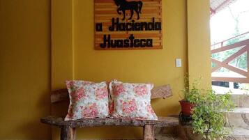 A wooden bench with floral cushions, a wall sign with a horse silhouette, and a potted plant.